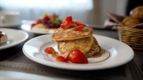 Stack of fluffy pancakes topped with fresh strawberries and maple syrup for.. Stock Photos