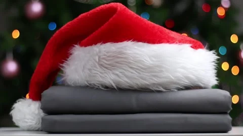A stack of folded bedsheets with a Santa hat. Stock Footage 143323860