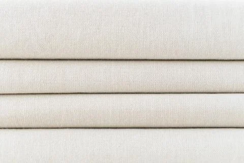Stack of folded beige woven fabric patterned background Stock Photos