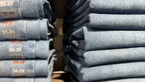 Stack of folded blue jeans with visible size labels, retail fashion concept.. Stock Footage 331090437