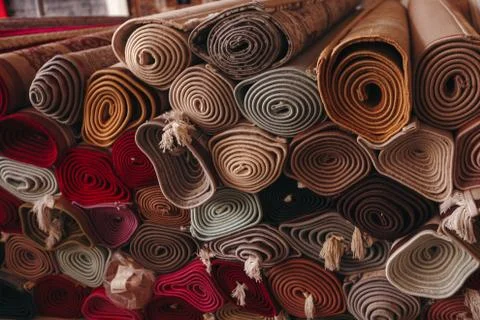 A stack of folded carpets of different colors, which can be seen in a carpet Stock Photos