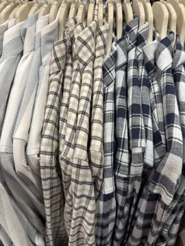 Stack of folded checkered shirts in various colors on hangers displayed on .. Stockfoto's