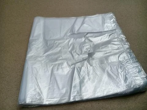 Stack of folded clear plastic shopping bags on brown background 库存照片