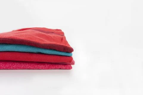 Stack of folded clothes, clean red cotton textile t-shirts on white backgroun Stock Photos