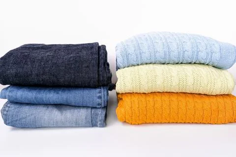 Stack of folded colorful sweater, pullover with blue jeans against white Stock Photos