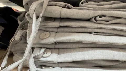 Stack of folded gray pants with buttons and drawstrings organized on wooden.. Stockbeeldmateriaal 331285990