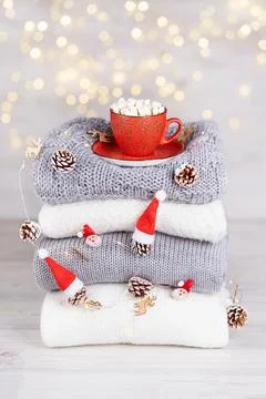 A stack of folded knitted sweaters, a red cup of cocoa with marshmallows Stock Photos