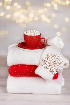 A stack of folded knitted sweaters, a red cup of cocoa with marshmallows 스톡 사진