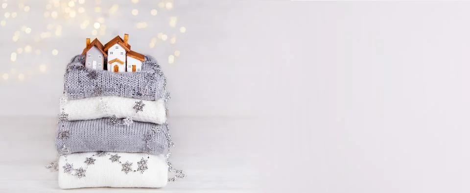 A stack of folded knitted sweaters, toy wooden houses Stock-Fotos