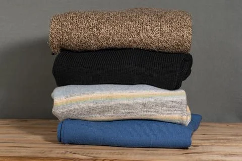 Stack of Folded Knitted Sweaters on Wooden Surface Stock Photos