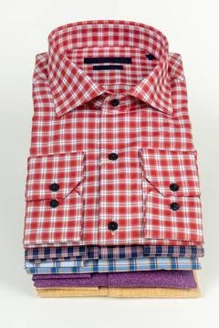 Stack of folded men's shirts in various colors and patterns, with a red pla.. Stock Photos