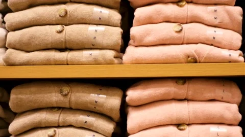 Stack of folded sweaters on shelf in store close-up front view. Stock Footage 220471891