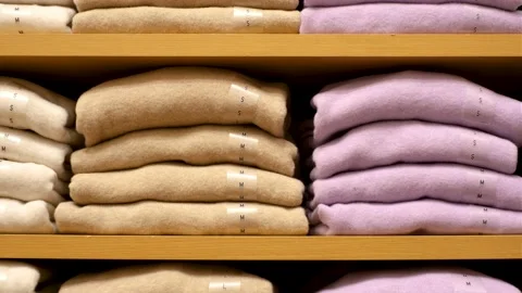 Stack of folded sweaters on a wooden shelf in store close-up front view. Stock Footage 220320240