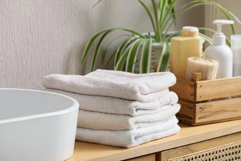 Stack of folded towels on bathroom countertop with toiletries Stock Photos