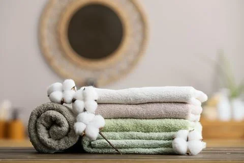 Stack of folded towels with cotton branches on wooden surface Stock Photos