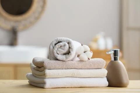 Stack of folded towels with cotton flower and soap dispenser Stock Photos