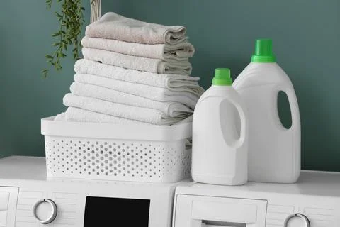 Stack of folded towels in laundry basket with detergent bottles Stock Photos