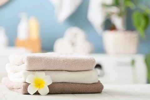 Stack of folded towels with plumeria flower in spa setting Stock Photos