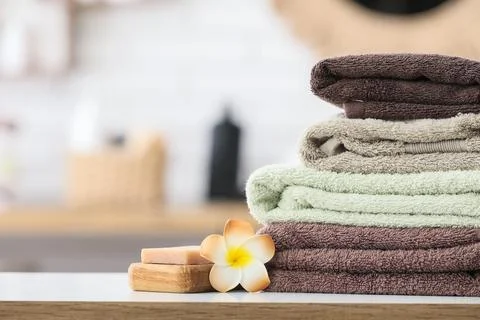 Stack of folded towels with soap and flower on table Stock Photos