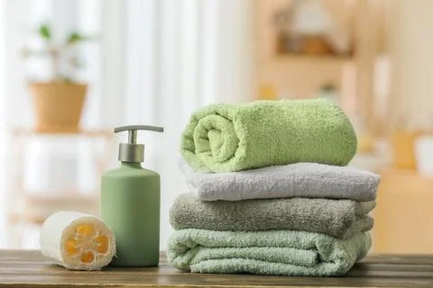 Stack of folded towels with soap dispenser and loofah Stock Photos