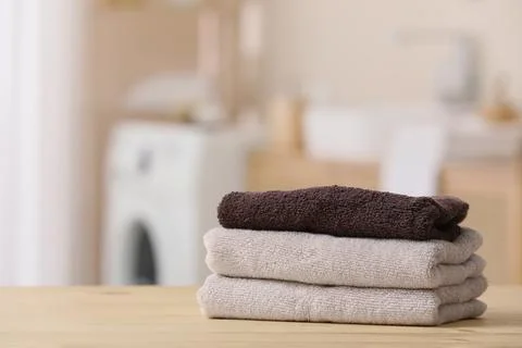 Stack of folded towels on wooden surface in laundry room Stock Photos