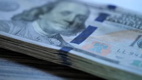 Stack of folded US dollars lies on wooden table. One hundred dollar bills. Stock Footage 243576500