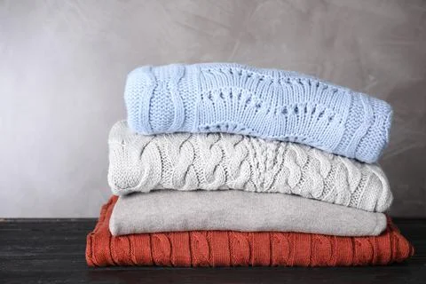 Stack of folded warm sweaters on black wooden table 스톡 사진