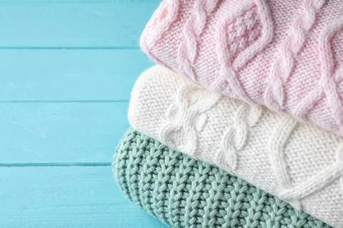 Stack of folded warm sweaters on turquoise wooden background, closeup 스톡 사진