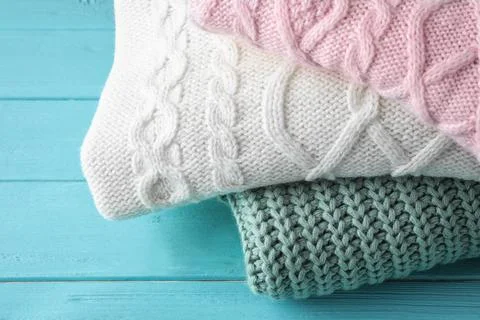 Stack of folded warm sweaters on turquoise wooden background, closeup Foto stock