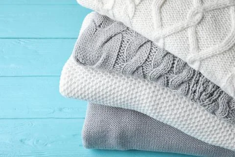 Stack of folded warm sweaters on turquoise wooden background, closeup 스톡 사진