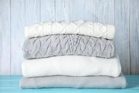 Stack of folded warm sweaters on turquoise wooden table Stock Photos