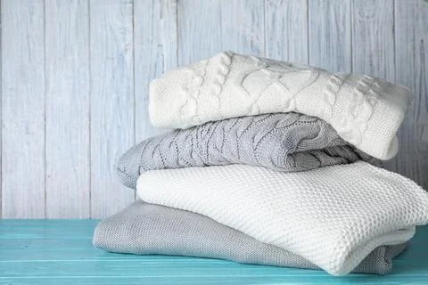 Stack of folded warm sweaters on turquoise wooden table 스톡 사진