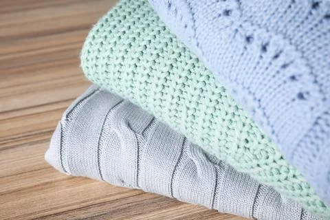 Stack of folded warm sweaters on wooden table, closeup 스톡 사진