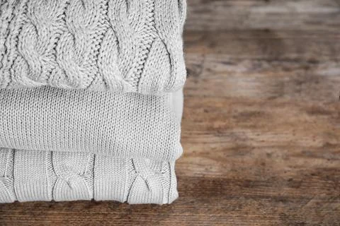 Stack of folded warm sweaters on wooden table. Space for text 스톡 사진