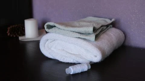 A stack of folded white and light green terry towels, a spool of white thread on Fotos de archivo
