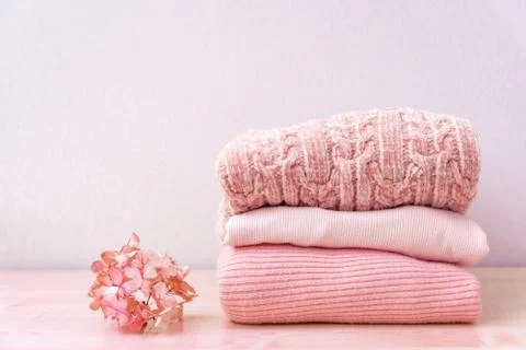 Stack of folded wool knitted sweaters in pink pastel colors laying on table for Stock Photos