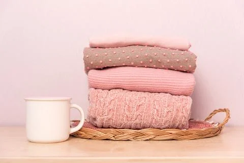 Stack of folded wool knitted sweaters or pullovers in pink pastel colors on t Stock Photos