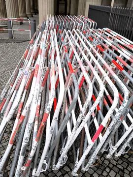 A stack of folding metal barriers with red and white stripes on a city pavement Stock Photos