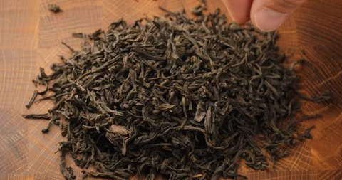 Stack of footage: Male hand picks tea leaves. Black tea. Dried tea leaves Stockbeeldmateriaal 122776327