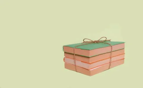 A stack of four books with colored covers tied with string laid out on a unif Stock Photos