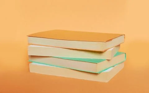 A stack of four books with colored covers is laid out on a uniform background Stock Photos