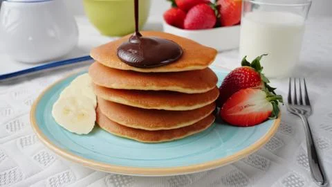 Stack of four golden pancakes with chocolate syrup and strawberries Stock Photos