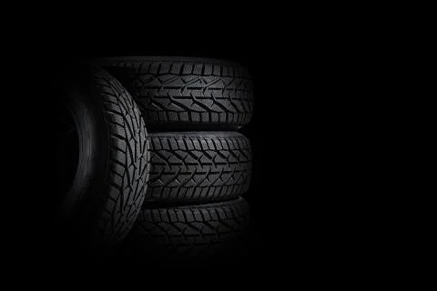 Stack of four new black tyres for winter car on black background Stock Photos