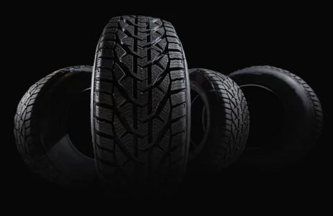 Stack of four new black tyres for winter car on black background Stock Photos