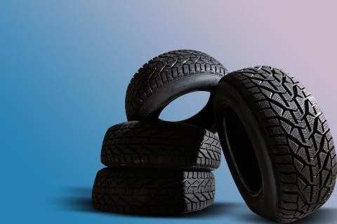 Stack of four new black tyres for winter car on blue background Stock Photos