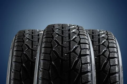 Stack of four new black tyres for winter car on blue background Stock Photos