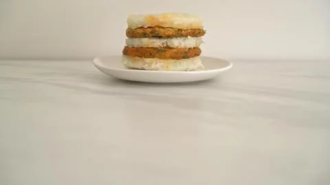 Stack of four veggie patties on a white plate in a simple setting Stock Photos