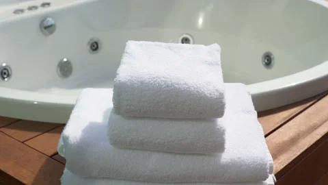 Stack of four white towels and blurry bathtub in background Video stock 139229877