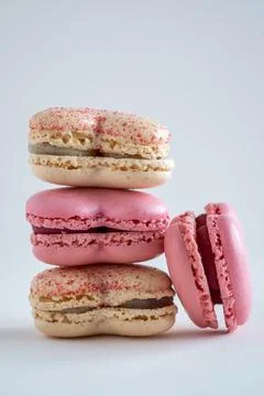 A stack of French macarons in pink and yellow with one macaron on the side 写真素材