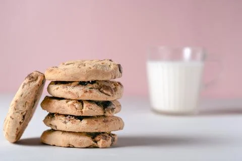 Stack of fresh chocolate and nut cookies next to a blurred glass of milk 스톡 사진